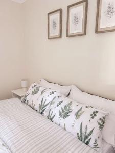 a white bed with two pillows and two pictures on the wall at Relaxing retreat near Norfolk Broads in Norwich