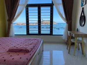 a bedroom with a large window with a bed and a desk at Ánh Dương in Quy Nhon