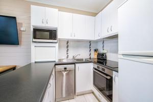 a kitchen with white cabinets and stainless steel appliances at Snow Ski Apartments 35 in Falls Creek +3 photos