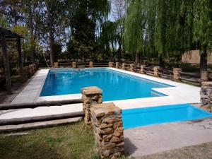 una piscina en un patio con una pared de piedra en Cabañas El Refugio del Atuel en San Rafael