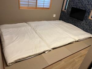 una cama con sábanas blancas en una habitación en Asagaya House, en Tokio