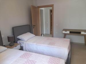 een kleine kamer met 2 bedden en een bureau bij Villa Elsi lower apartment in Kalámi
