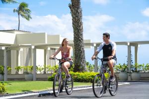 a man and a woman riding bikes down a street at The Kahala Hotel and Resort in Honolulu