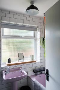 baño con lavabo rosa y ventana en Suburban Hideaway in Suffolk en Ipswich