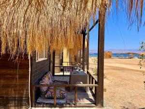 ein Haus mit einer Veranda mit Strohdach in der Unterkunft Al Khalil Beach Camp in Nuweiba