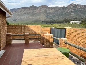 a patio with a wooden table and a brick wall at Dux in Montagu