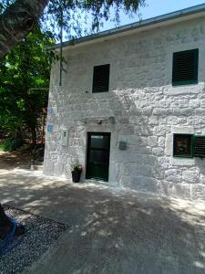 - un bâtiment en pierre blanche avec une porte verte dans l'établissement Kuća za odmor Grupković, à Ploče