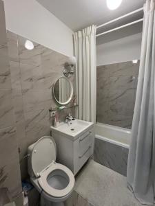 uma casa de banho com um WC, um lavatório e uma banheira em Confortabil si modern em Bucareste