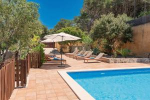 a swimming pool with lounge chairs and an umbrella at Boutique Hotel Oriola in Cala de Sant Vicenc