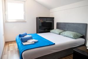 um quarto com uma cama grande com lençóis azuis e uma janela em Holiday Home Vemini em Mostar