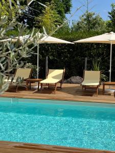 a group of chairs and umbrellas next to a pool at Hôtel Le Grain de Sable in Arès