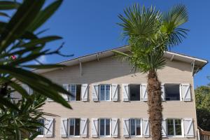 a palm tree in front of a building at Hôtel Le Grain de Sable in Arès
