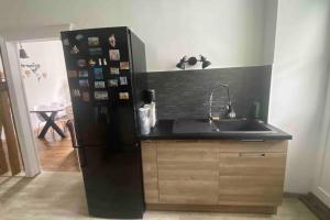 eine Küche mit einem schwarzen Kühlschrank und einer Spüle in der Unterkunft Appartement Dol de Bretagne centre in Dol-de-Bretagne