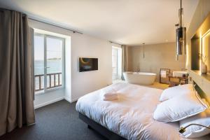 um quarto com uma cama, uma banheira e uma janela em ILE CEZON - Duplex de luxe avec magnifique vue mer em Landéda