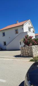a white building with a stone wall in front of a street at Apartments Ivan in Povljana