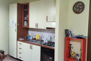 een keuken met witte kasten, een wastafel en een fornuis bij Villetta Casa Rosa in Castelluzzo