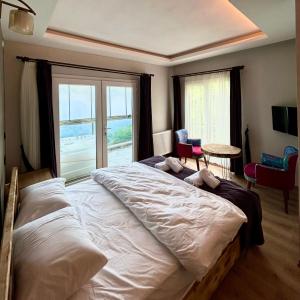 een slaapkamer met een groot bed en een groot raam bij Burahan Suit Hotel in Çamlıhemşin