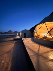 a glass house in the desert at night at Wild Oryx Camp Bubbles in Wadi Rum