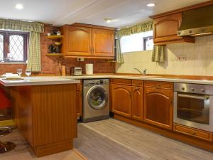 a kitchen with wooden cabinets and a washing machine at Weavers Cottage in Barnsley