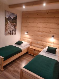 twee bedden in een kamer met houten wanden bij Bafia - pokoje gościnne in Bukowina Tatrzańska