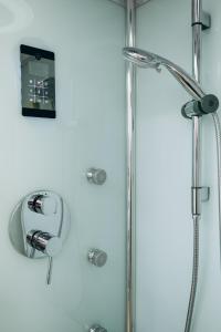 a shower in a bathroom with a clock on the wall at Kalos Apartments Catania in Catania