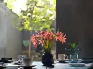 a vase filled with red flowers sitting on a table at Saffron Robes Living in Hikkaduwa