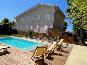 a backyard with a pool and chairs and a house at Hôtel Le Grain de Sable in Arès