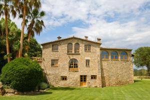 an old stone house with palm trees on a lawn at Mas Cufí in Serinyà