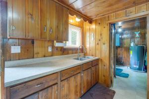 a kitchen with wooden cabinets and a sink at Charming Michigan Cottage with Sunroom and Lake Access in Hubbard Lake +17 photos