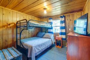 a bedroom with a bunk bed and a flat screen tv at Charming Michigan Cottage with Sunroom and Lake Access in Hubbard Lake