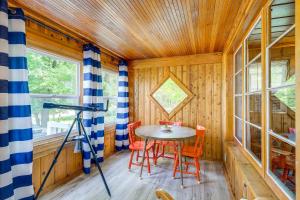 Charming Michigan Cottage with Sunroom and Lake Access في Hubbard Lake: غرفة بطاولة وكراسي وكاميرا