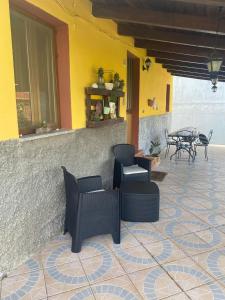 patio z krzesłami i stołami oraz żółtą ścianą w obiekcie Casa Vacanza Sa dommu de Teresa w mieście Nebida