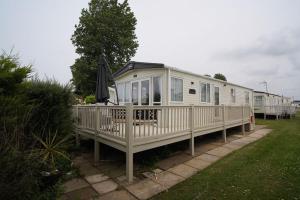 uma casa móvel com um alpendre e um guarda-chuva em Heacham Sunset lodge Platinum van em Hunstanton