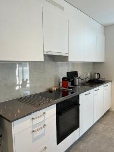 a kitchen with white cabinets and a black stove top oven at LabPark Terrace in Melano