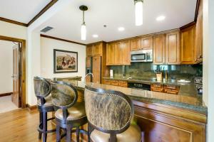 a kitchen with wooden cabinets and bar stools at Ski Resort Condo in Ritz-Carlton Aspen Highlands in Aspen