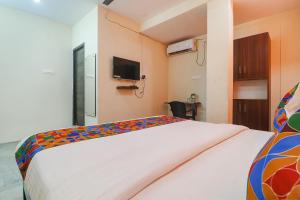 um quarto com uma cama e uma televisão na parede em FabHotel Lotus Park em Visakhapatnam