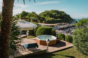 een hot tub in de tuin met een parasol bij Neptune Sea House - Beachfront in Agios Spyridon Corfu