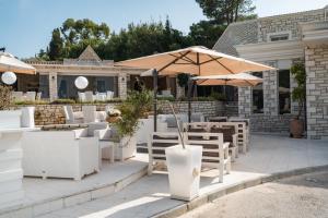 patio ze stołami, krzesłami i parasolami w obiekcie Neptune Sea House - Beachfront w mieście Agios Spirydon