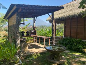 a garden outside a hut with a table and a fountain at Lembah Cinta Mayungan in Baturiti