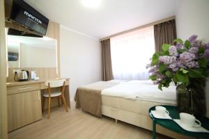 a hotel room with a bed and a vase of flowers at Ośrodek Wypoczynkowy Pod Dębem in Wójtowice