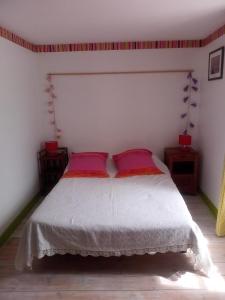 a bedroom with a white bed with two red pillows at chez Florence, chambres d'hôtes , Montrol Sénard in Montrol-Sénard