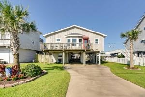 a house with a balcony and palm trees at Jamaica Beach Home with Surrounding Water Views! in Galveston