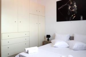 a bedroom with two white beds and a painting on the wall at Maria’s Sunset House in Megalochori