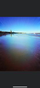 a beach with the ocean and some people in the water at Village view apartments in Tynemouth