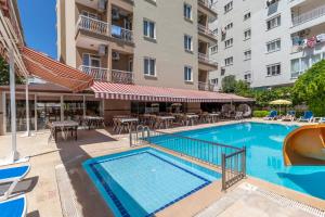 a swimming pool with tables and chairs next to a building at Lara Dinc Hotel in Antalya