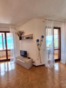 a living room with a television and a wall with curtains at Le Grigne Guest House in Oliveto Lario