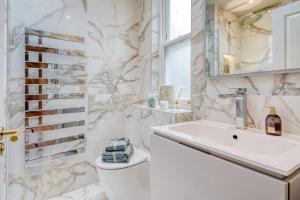 Marble Arch Suite 3-Hosted by Sweetstay في لندن: حمام أبيض مع حوض ومرآة