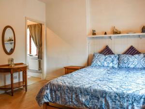 a bedroom with a blue bed and a mirror at Weavers Cottage in Barnsley