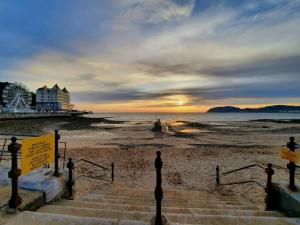 a beach with stairs and a pier and the ocean at Mona Lodge - 3 bed cottage in Llandudno in Llandudno