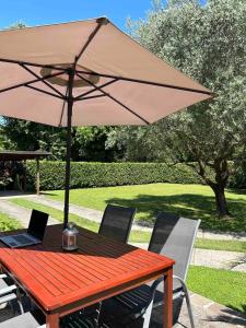 a wooden table with an umbrella and a laptop on it at La Casina apartament in Ferrara